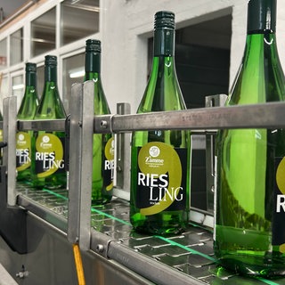 Frisch abgefüllte Riesling-Flaschen der Winzergenossenschaft Kallstadt auf einem Produktionsband.