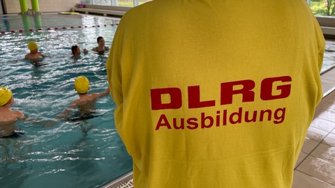Das Bild zeigt einen Ausbilder der DLRG in Landau bei einem Schwimmkurs für Kinder. Symbolbild: Immer weniger Kinder bekommen einen Platz im Schwimmkurs