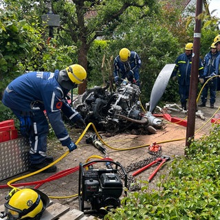 Einsatzkräfte schneiden den Motor des abgestürzten Kleinflugzeugs in zwei Teile, um ihn besser abtransportieren zu können.