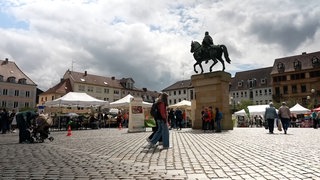 Schülerinnen laufen über den Rathausplatz in Landau, im Hintergrund stehen Infostände und Zelte: Am 20. Mai feiert Landau das "Demokratiefest".