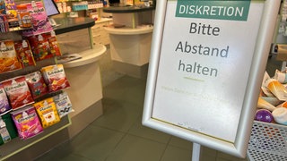 Ein Schild weist in einer Apotheke darauf hin Abstand zu halten.