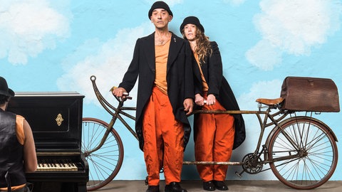 Zwei Clowns mit ihrem "Flugfahrrad" begleitet von Piano-Musik: Das Ensemble "Leandre Clown" wird in Ludwigshafen ihr Stück "Fly me to the Moon" zeigen.