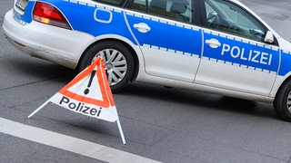 Ein Polizeifahrzeug steht zur Absicherung auf einer Straße. 
