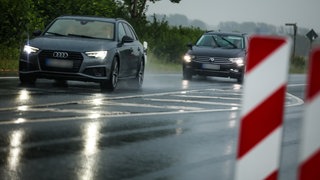 Zwei Autos fahren bei Regen auf einer Landstraße (Symbolbild). Das Landgericht Frankenthal hat entschieden, dass ein Raser aus Ludwigshafen nach einem Unfall den Schaden zahlen muss, obwohl ihm die Vorfahrt genommen wurde.