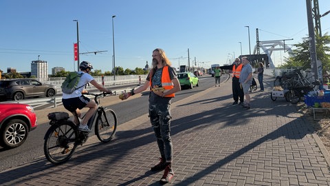 Ehrenamtliche an der Auffahrt der Konrad-Adenauer-Brücke in Ludwigshafen. Jeden zweiten Mittwoch verteilen sie an Fahrradfahrer Kaffee, Obst und Muffins.