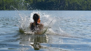 Ein Mädchen springt ins Wasser. Rund um Mainz gibt es einige Badeseen.