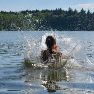 Ein Mädchen springt ins Wasser. Rund um Mainz gibt es einige Badeseen.
