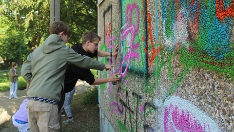 Zwei Jugendliche besprühen das alte Hallenbad in Oppenheim mit Graffiti.