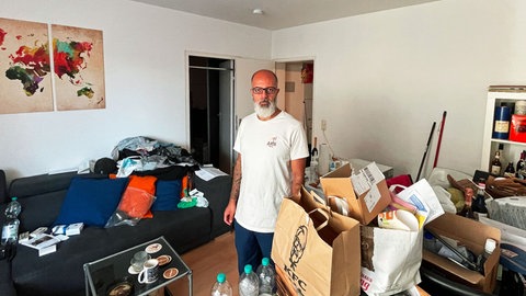 Mieter John Bader steht in seinem voll gestellten Wohnzimmer. 