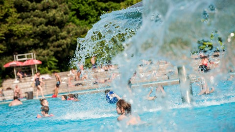 Dutzende Kinder planschen in einem Freibad.