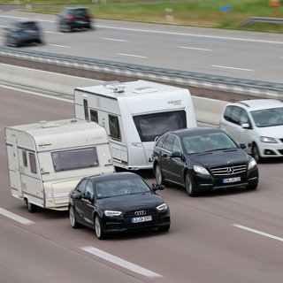Zwei Wohnwagen-Gespanne fahren nebeneinander auf der Autobahn.