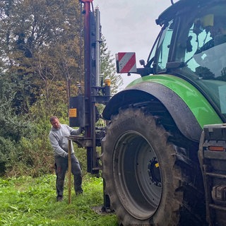 Zwei Männer errichten am Rande eines Ackers einen Zaun. In Rheinhessen werden weitere Zäune aufgestellt, um die afrikanische Scweinepest einzudämmen. 
