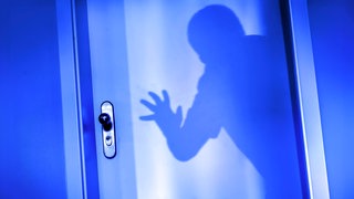Ein Einbrecher will im Schutz der Dunkelheit eine Wohnungstür aufbrechen.