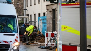 Mitarbeiter der Mainzer Netze untersuchen die Stelle, an der die Schillerstraße in Mainz durch einen Wasserrohrbruch unterspült wurde.