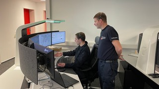 Zwei Feuerwehrmänner in der Feuerwehrleitstelle in Mainz.