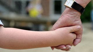 Eine Frauenhand hält eine Kinderhand.