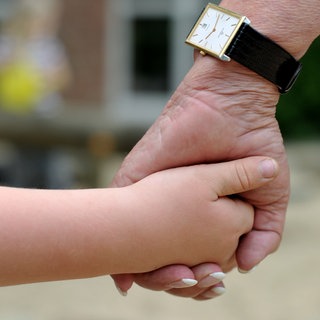 Eine Frauenhand hält eine Kinderhand.