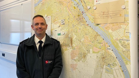 Jens Olschweski, Leiter des Tauchdienstes der Feuerwehr Mainz, steht vor der Karte zur Wasserrettung in der Feuerwehrleitstelle.