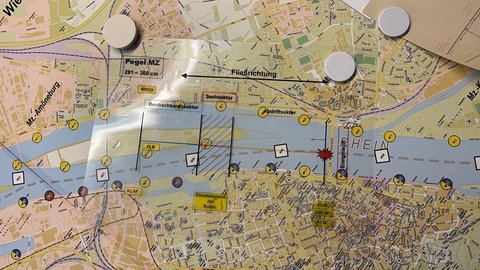 Auf einer Rhein-Karte der Feuerwehr Mainz für die Wasserrettung liegt eine Folie, die anzeigt, wo die Feuerwehr die Person im Rhein beim Eintreffen der Rettungskräfte erwartet.