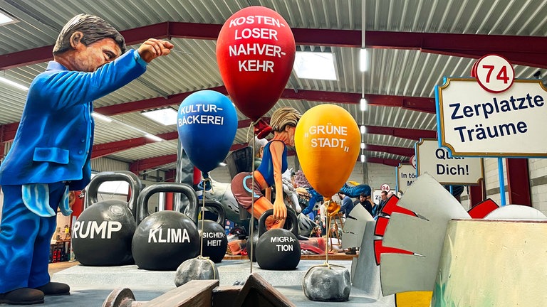 Der Mainzer Finanzdezernent Günter Beck (Bündnis 90Die Grünen) steht vor Luftballons auf denn Projekte stehen, die sich die Stadt jetzt nicht mehr leisten kann. 