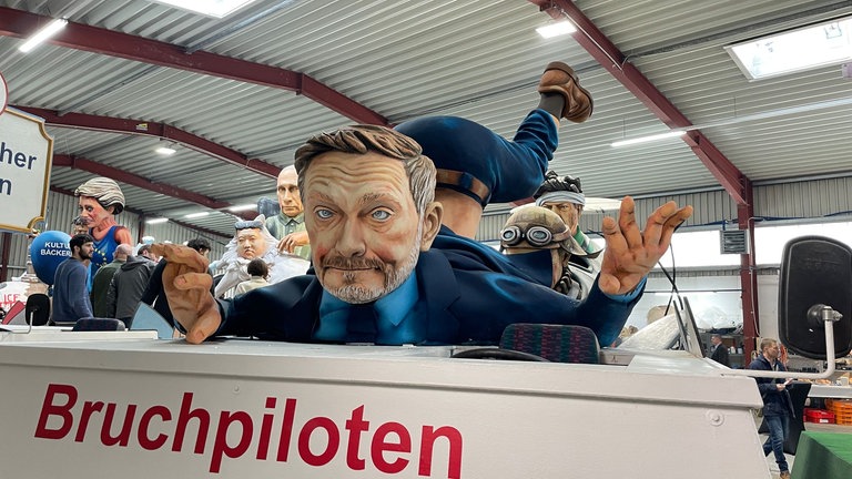 Motivwagen für den Mainzer Rosenmontagszug 2025: Bundeskanzler Olaf Scholz als Bruchpilot, Christian Lindner (FDP) ist schon vorher aus dem Flugzeug gefallen. 