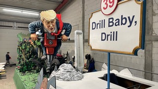 Motivwagen für den Rosenmontagszug 2025 in Mainz: US-Präsident Donald Trump sucht mit einem großen Bohrer nach Bodenschätzen. 
