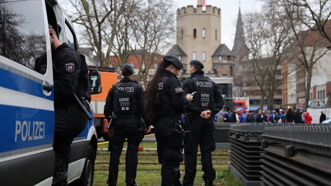 Polizisten warten an Karneval an der Zugstrecke des Kölner Rosenmontagszuges. 