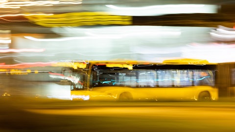 Ein Bus fährt am frühen Morgen über eine Straße (Aufnahme mit Langzeitbelichtung).