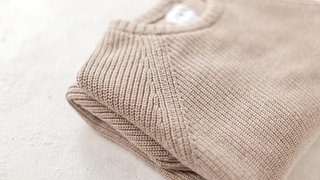 Nahaufnahme eines gestrickten Herrenpullovers aus Wolle auf einer Strickmaschine. 