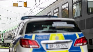 Ein Auto der Bundespolizei steht am Mainzer Hauptbahnhof vor einem Bahngleis mit Zug. 