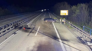 Auf der A61 bei Gundersheim ist eine Frau mit ihrem Auto verunglückt. Das kaputte Auto, eine große Ölspur und der Motorblock des Autos sind auf der Autobahn zu sehen