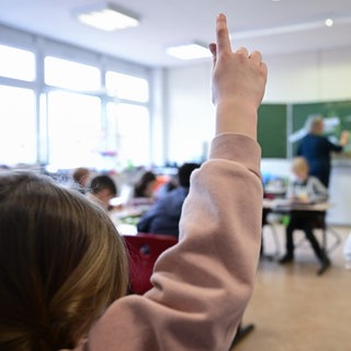 Ein Kind meldet sich in einer Grundschulklasse