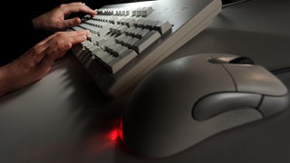 Zwei Hände tippen auf einer Computer-Tastatur.