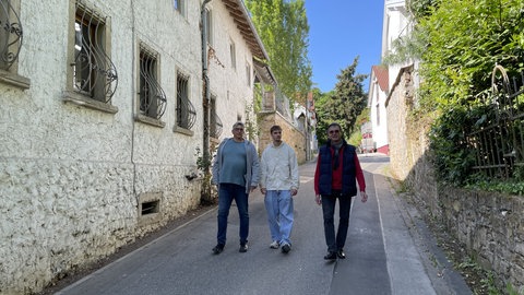 Tim Sieper, der jüngste Bürgermeister Deutschlands, geht zusammen mit seinem Vater und dem Ersten Beigeordneten durch eine Straße in Eckenroth 