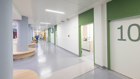 Die Flure der Zentralen Notaufnahme sind breit und freundlich gehalten. Monitore an der Wand zeigen an, wie viele Patienten sich aktuell in Behandlung befinden und wie viele noch warten müssen.