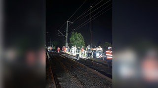 Mehrere Rettungskräfte sind auf den ausgeleuchteten Gleisen. Ein Arbeiter hatte sich bei Wiesbaden vor einer herabstürzenden Oberleitung gerettet.