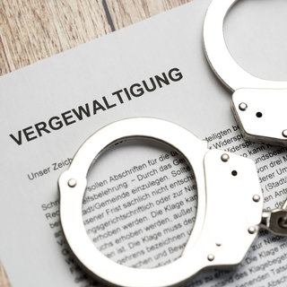 Handschellen liegen auf einem juritischem Papier: Das Landgericht Mainz hat einen Krankenpfleger verurteilt, der sein Kollegin vergewaltigt hatte. 