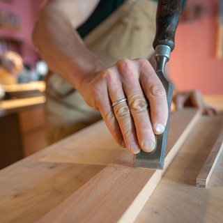 Ein Schreiner arbeitet allein an einer Werkbank.