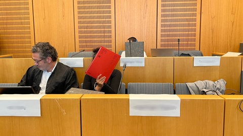 Ein Rechtsanwalt und zwei der Angeklagten eines großen Drogenprozesses sitzen im Landgericht Mainz. Die Band aus sechs Personen soll Drogen im Wert von mehr als 1,7 Millionen Euro verkauft haben
