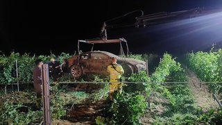 Ein Auto hängt am Kran eines Abschleppwagens. Es war bei Bad Kreuznach in einem Weinberg gelandet