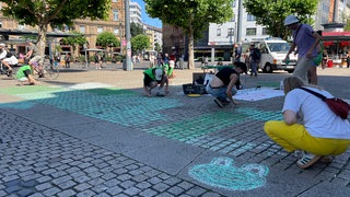 Mitglieder der Bewegung "Fridays for future" malen Teile des Mainzer Bahnhofsvorplatzes mit grüner Kreide an.