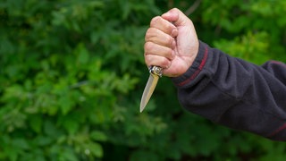 Eine Männerhand hält ein Messer. In der Mainzer Oberstadt hat ein Mann mit einem Messer Spaziergänger bedroht