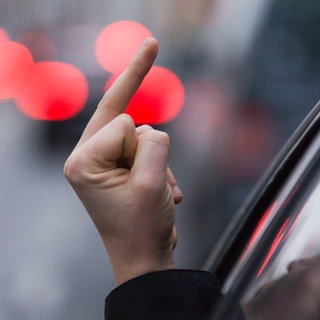Einen sogenannten "Stinkefinger" zeigt ein Autofahrer aus seinem Auto.