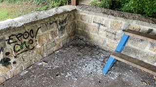 In einer Ecke der Grillhütte in Stadtecken-Elsheim liegt ein Häufchen Asche. An der Wand ist ein Graffiti-Schriftzug