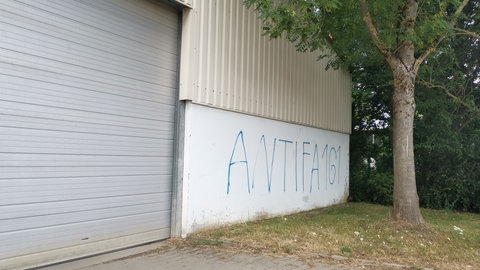Auf einer weißen Wand steht der Schriftzug Antifa 161, in blauer Farbe aufgesprüht.