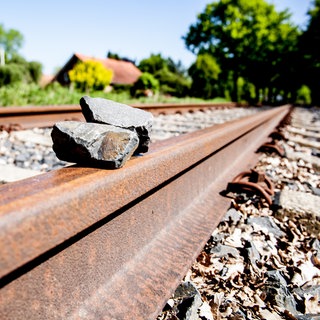 Zwei Steine liegen auf Bahnschienen. (Symbolbild)