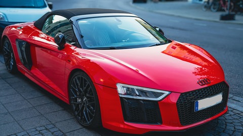 Ein roter Audi R8 Spyder parkt an einer Straße - diese Autos haben bis zu 620 PS.