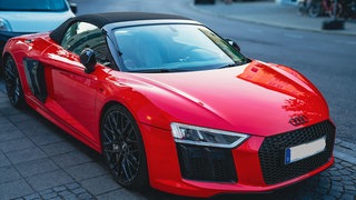 Ein roter Audi R8 Spyder parkt an einer Straße - diese Autos haben bis zu 620 PS.