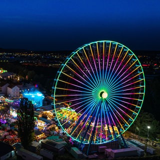 Der Jahrmarkt in Bad Kreuznach mit seinem Riesenrad leuchtet in der Nacht.