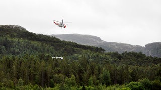Ein Rettungshubschrauber fliegt in Norwegen über Wälder (Symbolbild).